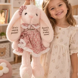 Iepuriță cu rochiță florală, 45 cm – Selena, detaliu frontal al personalizării Iepuriță roz cu numele Selena pe rochița florală, ținută de un copil în rochie crem, cu mesaje vizibile pe urechi.